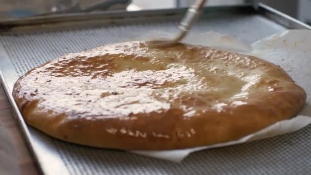 Baker hand inflicts egg mixture with brush on hot pie after baking in bakery — Stock Video