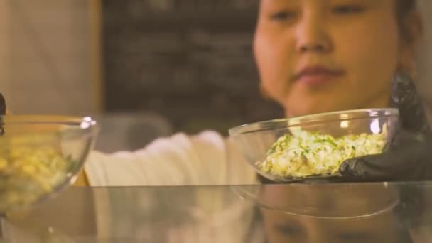 Женщина кладет миску с салатом в витрине магазина ресторан для бизнес-ланча — стоковое видео