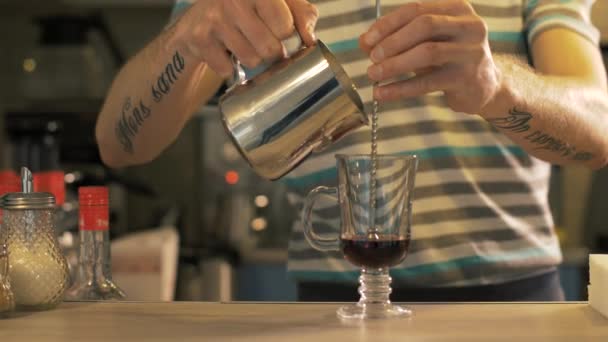 Barista gieten melk in glazen koffiekopje in cafetaria close-up — Stockvideo