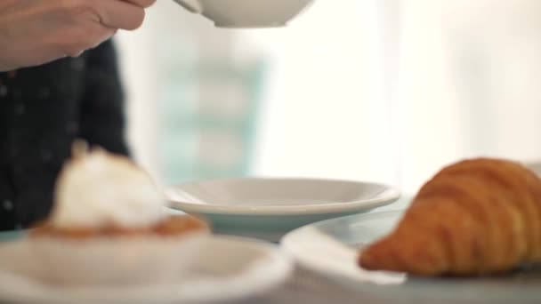 Woman drinking coffee from white cup at table in bakery cafe close up — Stock Video