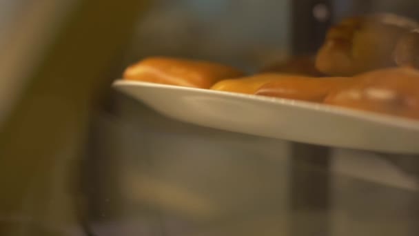 Pasteles horneados en bandeja en el café de confitería. Patatas frescas y calientes en escaparate — Vídeo de stock