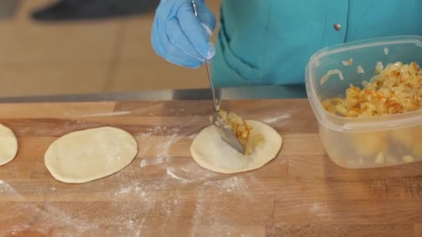 Chef panadero relleno de masa antes de hornear empanadas en la mesa de madera en la pastelería — Vídeos de Stock