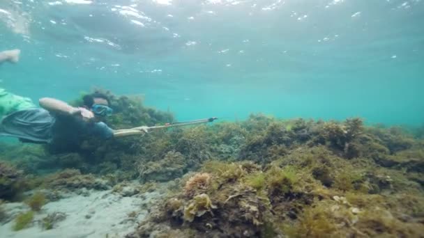 Tiro subaquático de um jovem pescador com uma lança à procura de peixe — Vídeo de Stock