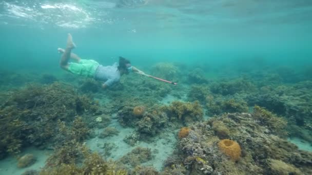 Un hombre con arpón cazando peces en el océano azul . — Vídeo de stock