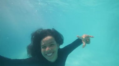 Young attractive funny girl with child smiling aand shouting diving underwater.