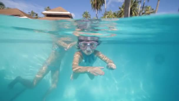Dziecko dziewczyna w masce do pływania nurkowanie w basenie wraz z mamą na wakacjach. — Wideo stockowe