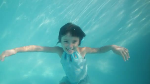 Happy souriant adorable enfant fille danse sous l'eau en regardant la caméra . — Video