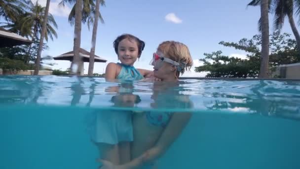 Dziecko dziewczyna i mama kąpiel w basenie z wężem zabawki w tropikalnym hotelu z palmami. — Wideo stockowe