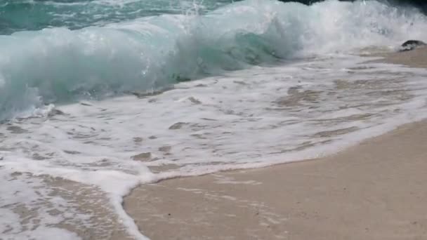 Wielkie falujące fale z piankami morskimi rozpryskujące się na białym piasku plaży. — Wideo stockowe