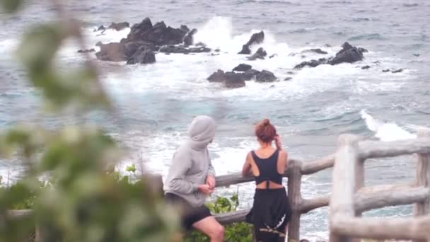Egy férfi és egy nő nézi a gyönyörű kilátás nyílik a hullámos óceán. — Stock videók
