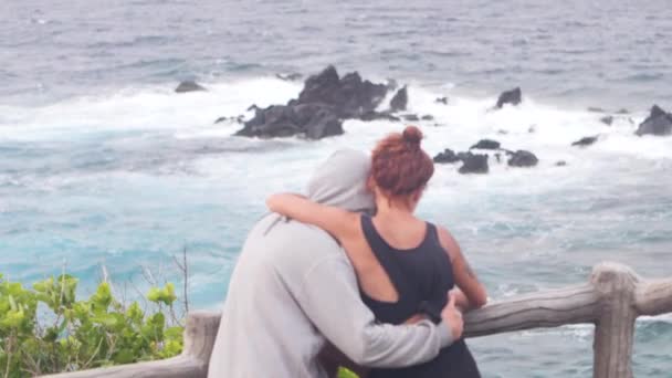 Vista trasera de una pareja abrazándose y disfrutando de la vista del mar . — Vídeos de Stock