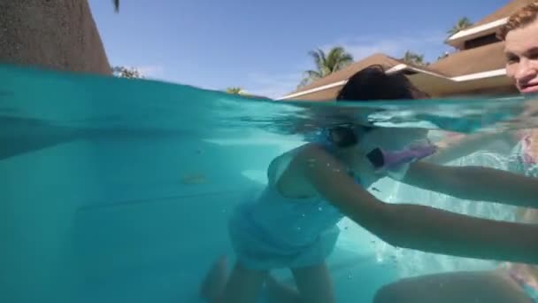 Child girl in swimming mask diving in pool, moms looking after her on vacation. — Stock Video