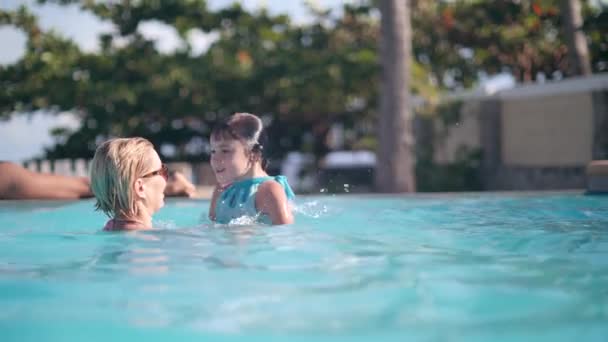 Mom is playing with child daughter in pool, throwing her in air and diving. — 비디오