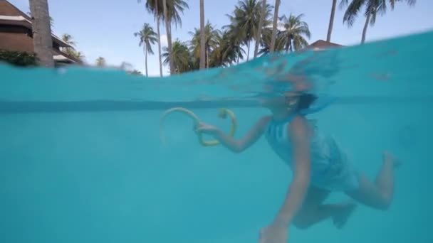 Niña nadando en piscina con skake de juguete en la mano en hotel tropical, vista lateral . — Vídeos de Stock