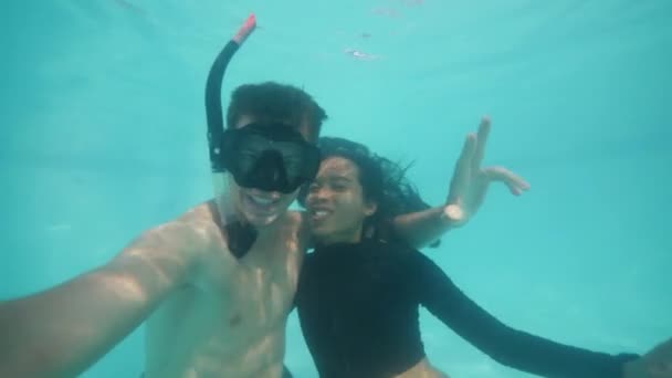 Bloggers jovencito y chica buceando bajo el agua en la piscina haciendo selfie y besándose . — Vídeos de Stock