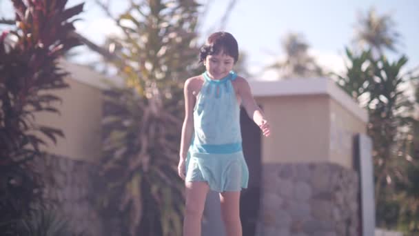 Счастливая маленькая девочка идет по стороне бассейна и прыгает в воду . — стоковое видео