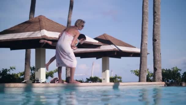 Mutter wirft Kind im Sommerurlaub in Pool von Urlaubshotel. — Stockvideo