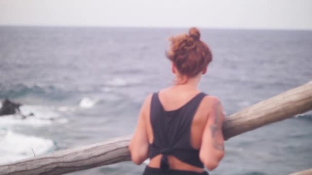 Woman with a red hair looking the view of the ocean on a windy day. — 비디오