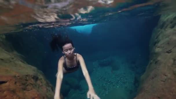 Підводний постріл: молода жінка плаває під водою в чистому природному басейні . — стокове відео