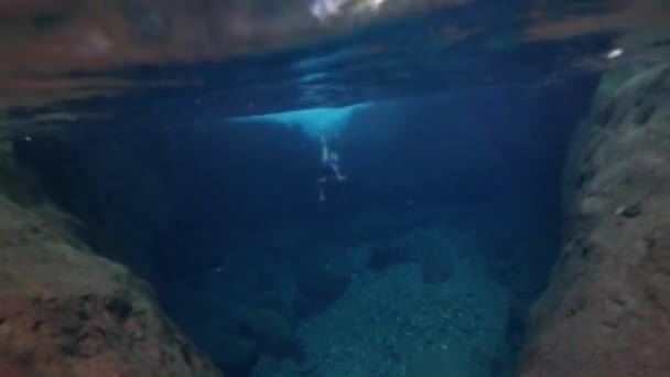 Eine junge Frau schwimmt unter Wasser in einem Wasserfall. — Stockvideo