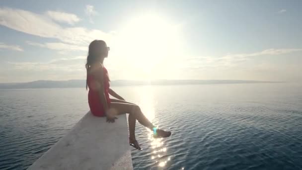 Een jonge vrouw zittend aan de rand van een boot met prachtig uitzicht op zonlicht. — Stockvideo
