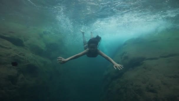 Młoda piękna kobieta pływa pod wodą w wiosennym wodospadzie. — Wideo stockowe