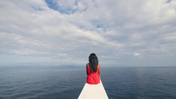 En kvinna sitter på kanten av en segelbåt och tittar på horisonten. — Stockvideo
