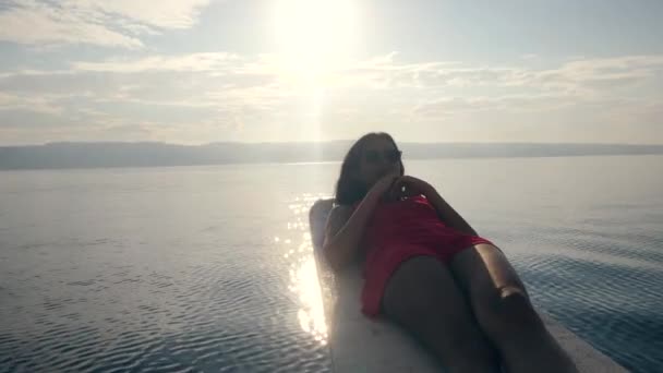 Женщина в красном платье делает хрустящие упражнения на краю лодки на рассвете . — стоковое видео