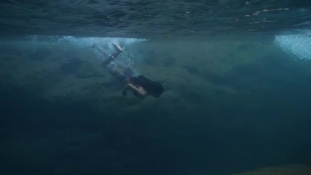 アクティブな若い女性が泳ぎ、自然のままの滝の春に水中で潜水します. — ストック動画