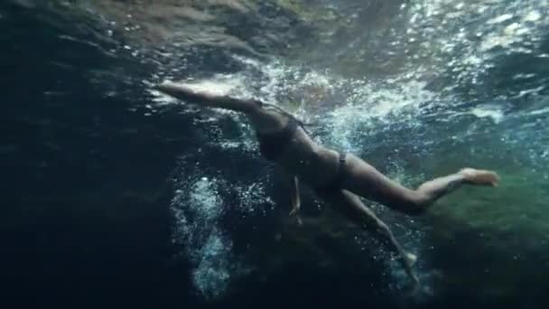 Una mujer nadando y buceando bajo el agua en una piscina natural con agua cristalina — Vídeo de stock