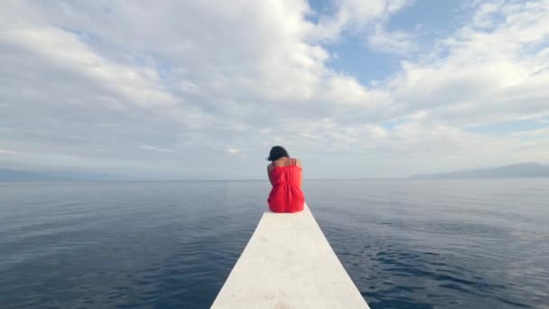 Back view of a sad young woman sitting alone on the edge of the boat. — Stock Video