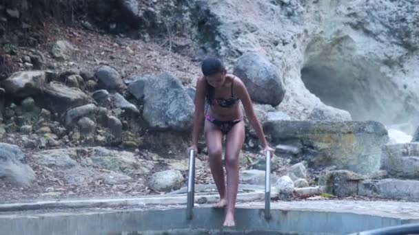 A slim woman in a bikini in a natural hotspring pool. — 图库视频影像
