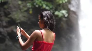 Şelalede yarı vücut, akıllı telefon kullanarak selfie çeken bir kıza ateş ediyor..
