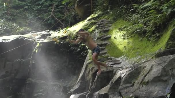 Fülöp-szigetek, Valencia 01-24-2020: Egy turista ugrik egy lépcsőzetes vízesés. — Stock videók