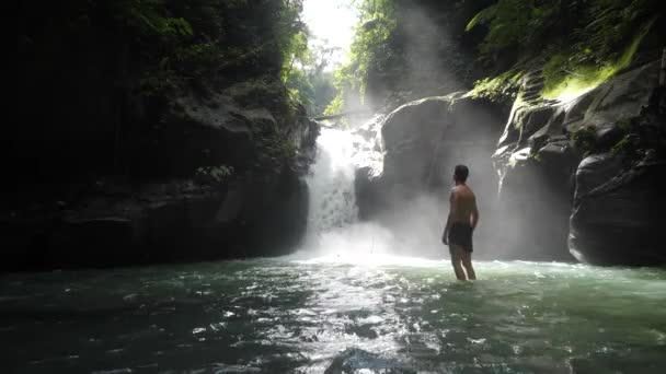 Homme heureux debout devant une cascade se sentant libre et prend une respiration . — Video