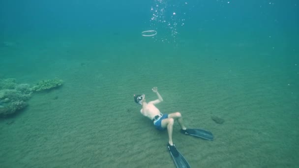 Мужчина фридайвер, дующий пузырьковые кольца под водой . — стоковое видео