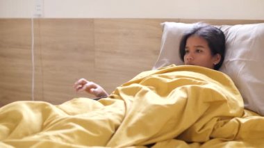 Hasta Asyalı kız yatakta dinleniyor vücut ısısını ölçüyor ve öksürüyor..