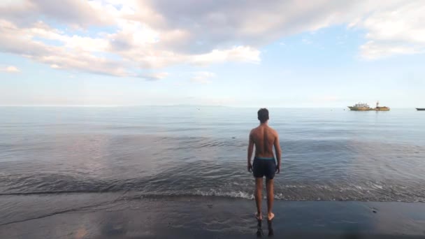 Yaz günü sahilde ayakta duran ve yürüyen erkeksi bir adam.. — Stok video