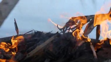 Ateş yakan adamların elleri Hindistan cevizi yapraklarını ve odunları yakıyor..