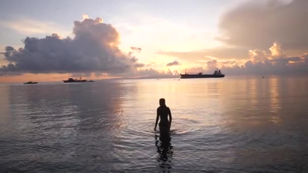 Σέξι γυναίκα σιλουέτα με τα πόδια στο νερό στην παραλία νωρίς το πρωί. — Αρχείο Βίντεο
