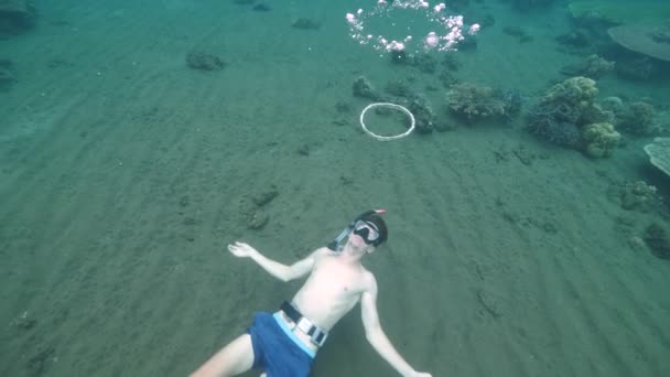 Człowiek uczący się jak zrobić bąbelkowy pierścień pod wodą. — Wideo stockowe