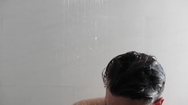 Jeune homme dans la douche laver les cheveux avec un shampooing cosmétique . — Video