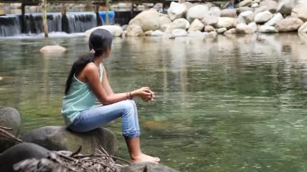 Menina feliz sentado em uma primavera fria gosta de espirrar a água no dia de verão . — Vídeo de Stock