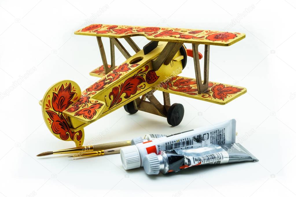 Toy airplane painted in khokhloma style, acrylic paints and brushes on white background