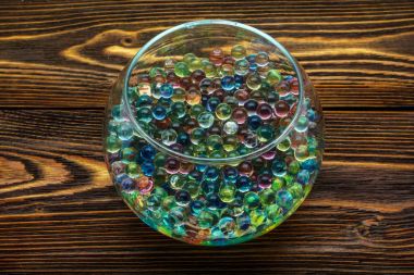 Colored hydrogel balls in a glass vase on old wooden table clipart