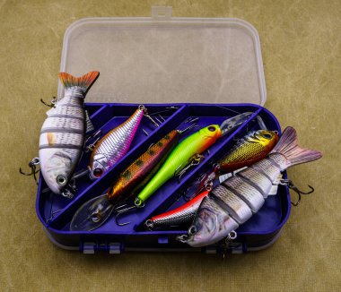 Baits for fishing on canvas background.  Several wobblers of different colors in the box for fishing gear. clipart