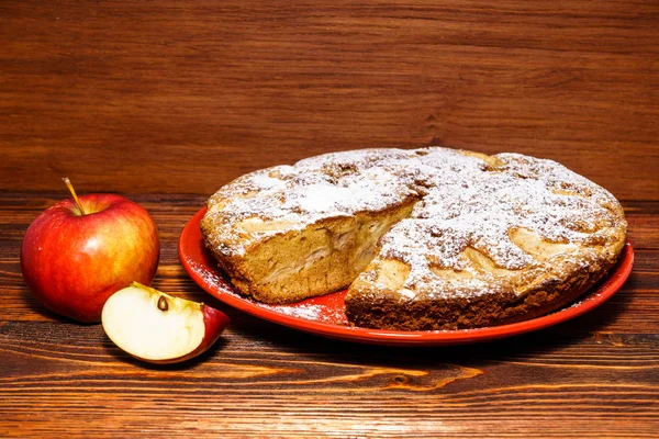 Manzanas y tarta de manzana recién horneada sobre un fondo rústico de madera oscura . — Foto de Stock