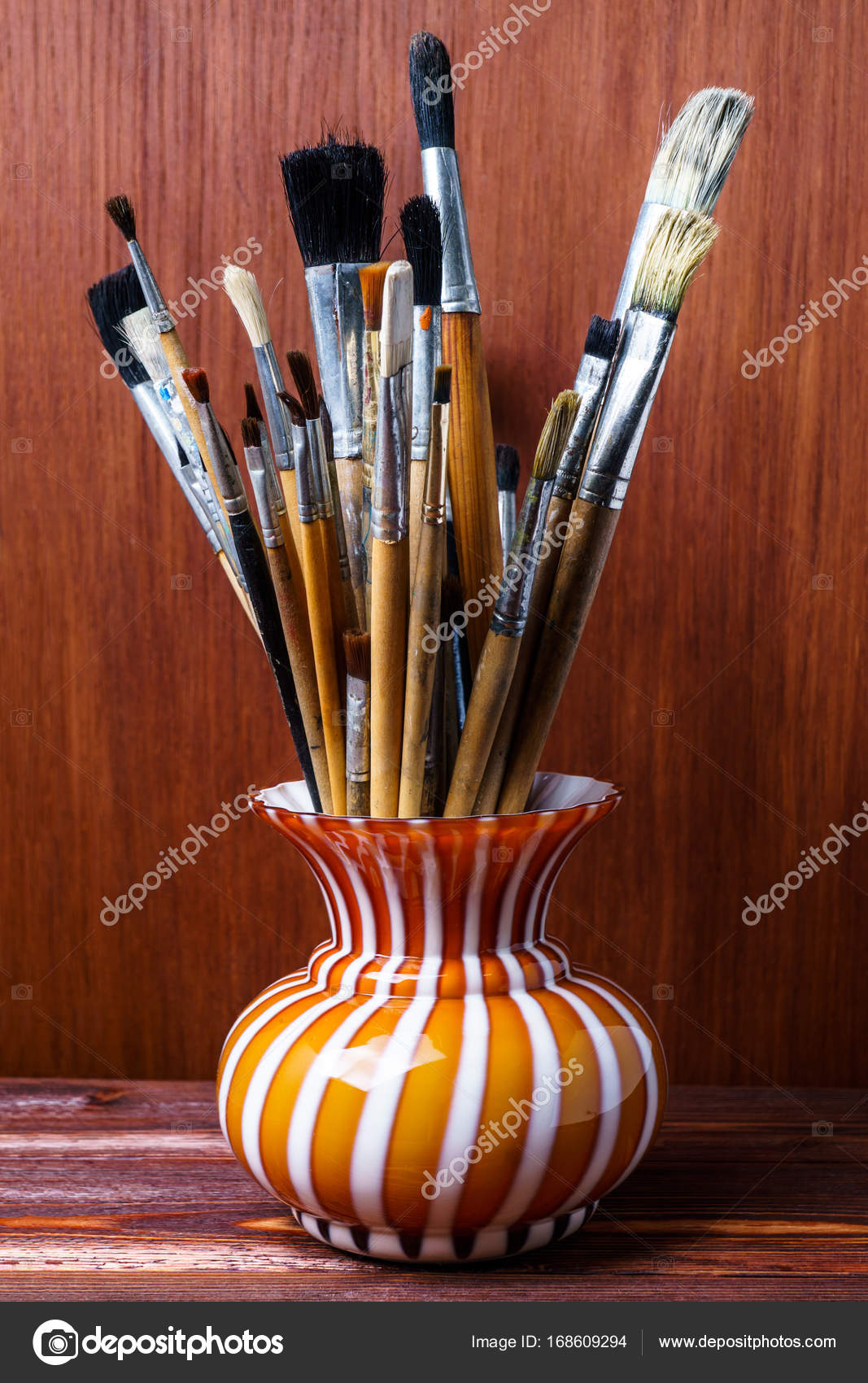 Assorted Dirty Brushes In A Vase On A Wooden Background Used