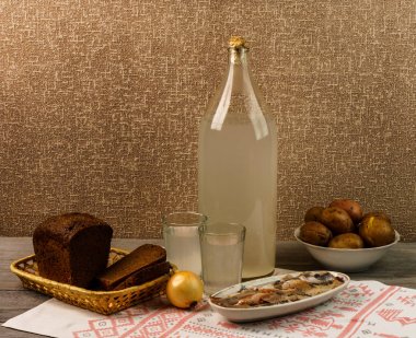 Ukrayna ulusal içecek ve atıştırmalık. Eski tahta masadaki büyük şişe ve bir bardak kaçak içki. Rus votka ve aperatif.