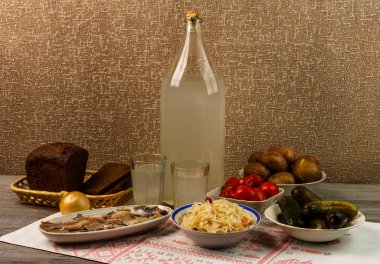 Ukrayna ulusal içecek ve atıştırmalık. Eski tahta masadaki büyük şişe ve bir bardak kaçak içki. Rus votka ve aperatif.